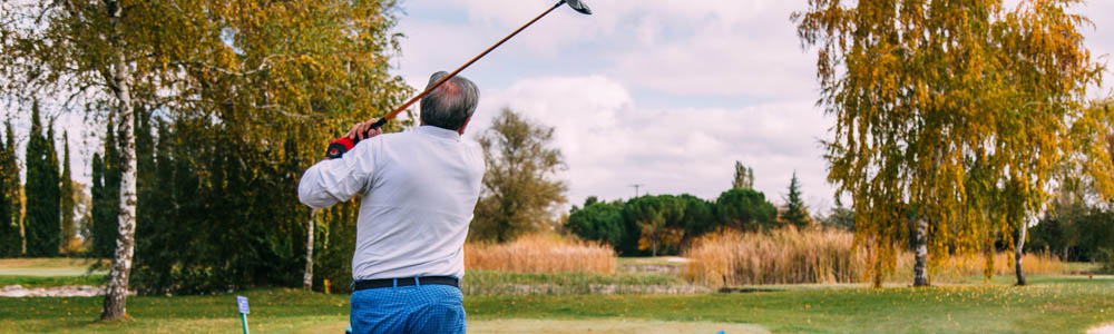 Older male golfer driving off on the golf course Older male golfer driving off on the golf course